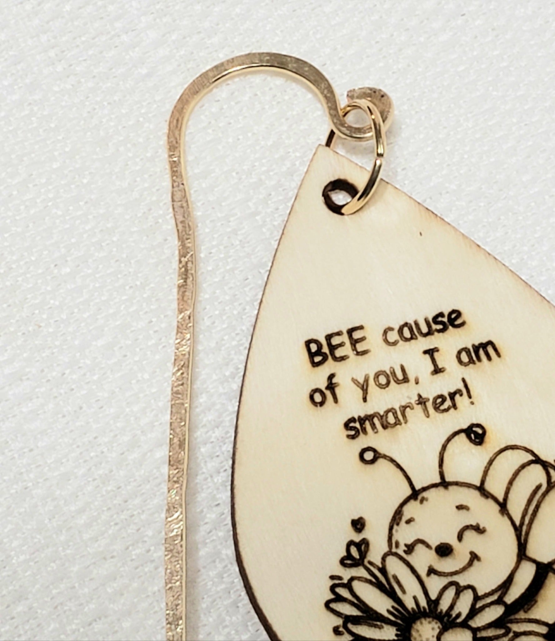 Wooden charm hangs from a hand shaped copper wire that is hammered for texture and sturdiness.